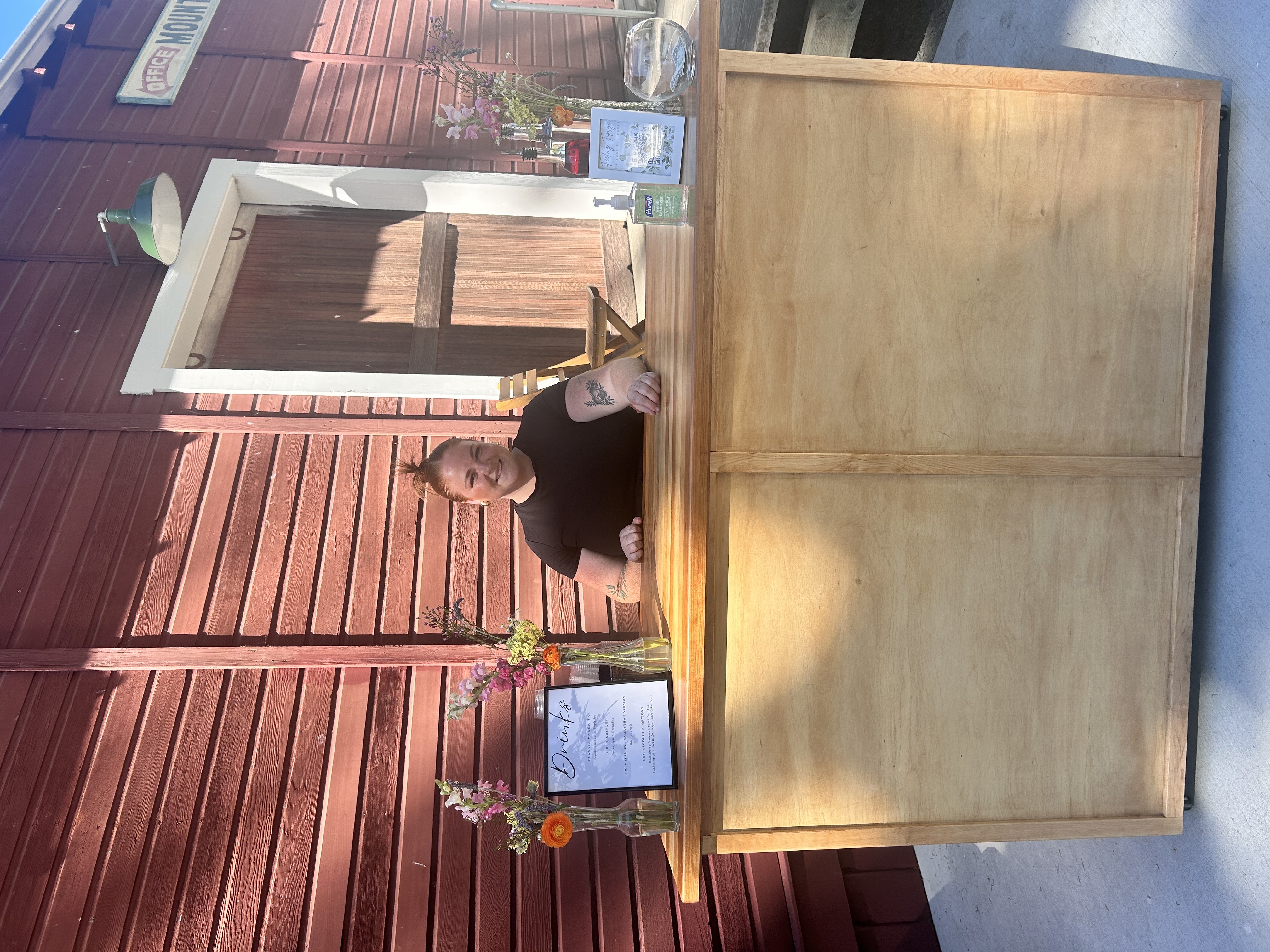 Sarah working behind a bar at an outdoor event with menus and flowers