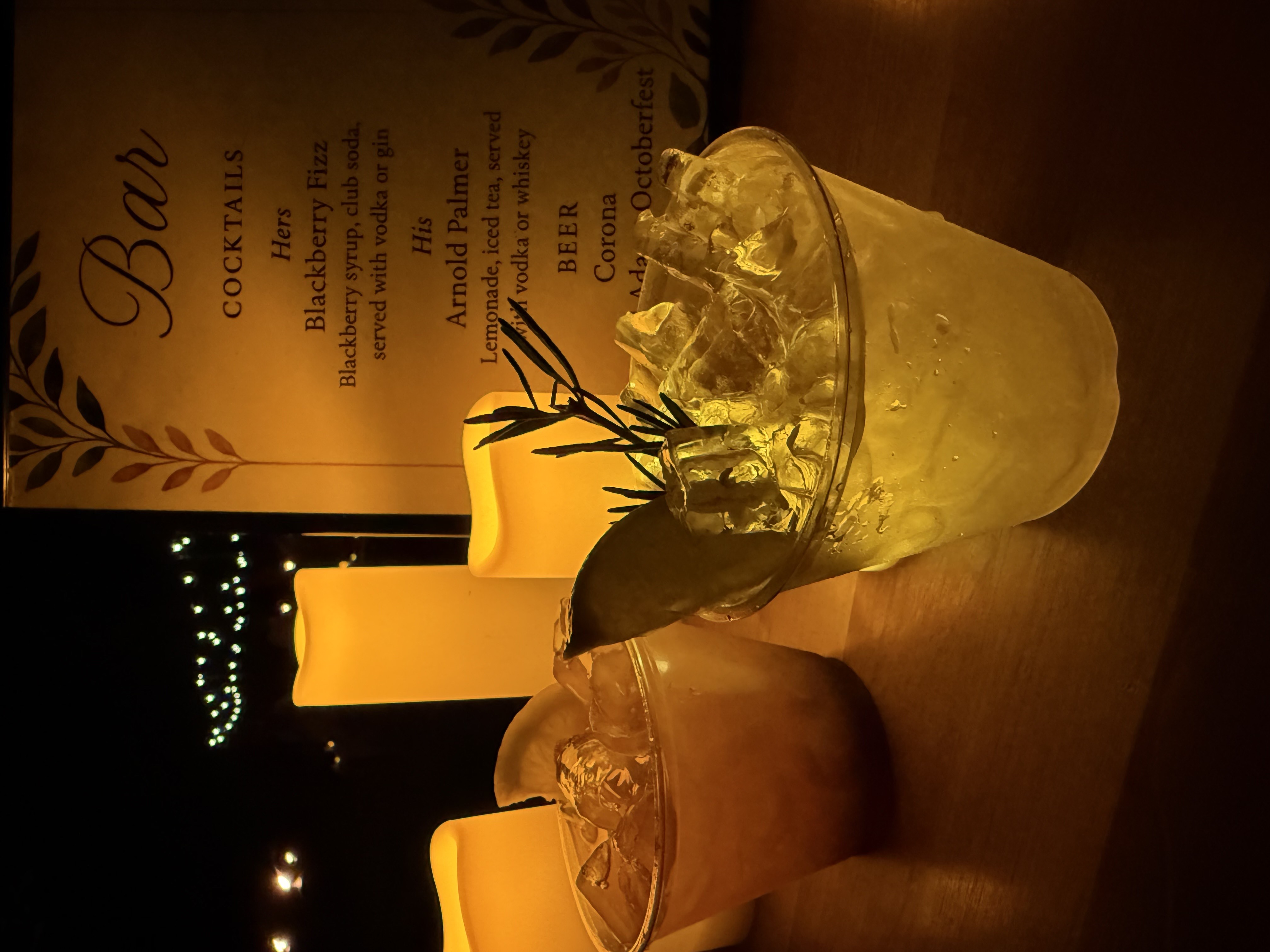 a mojito and bourbon smash cocktails lit by candles on a table